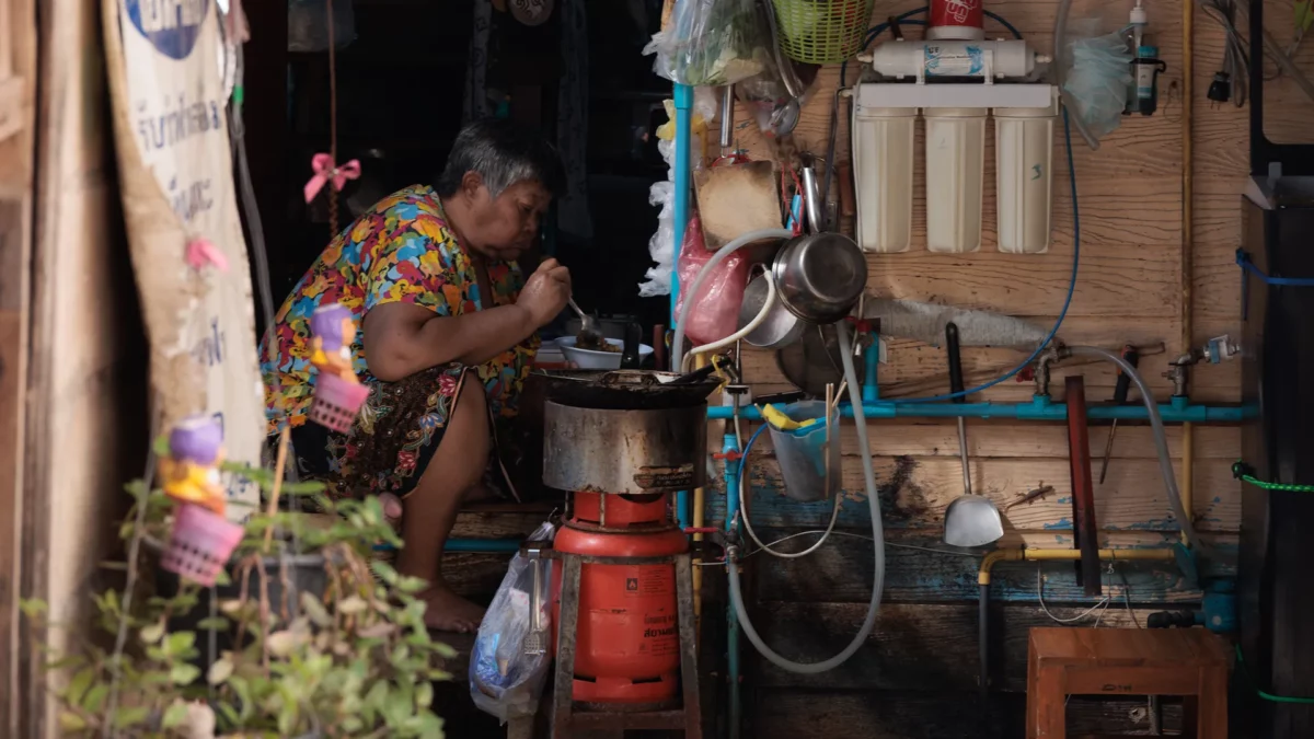 Old Thai woman eating in a street alley of Bangkok, Thailand