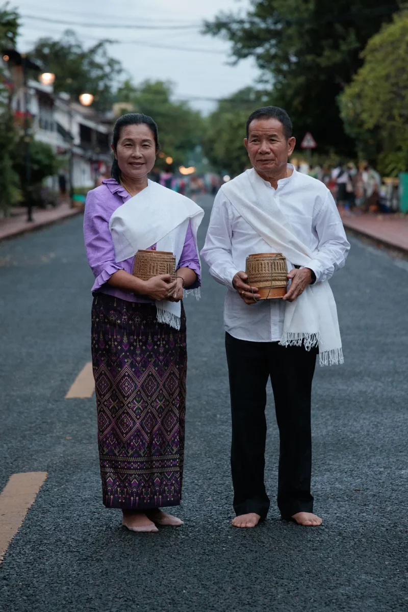 Asian couple posing in the street during the alms ceremony in Luang Prabang, Laos