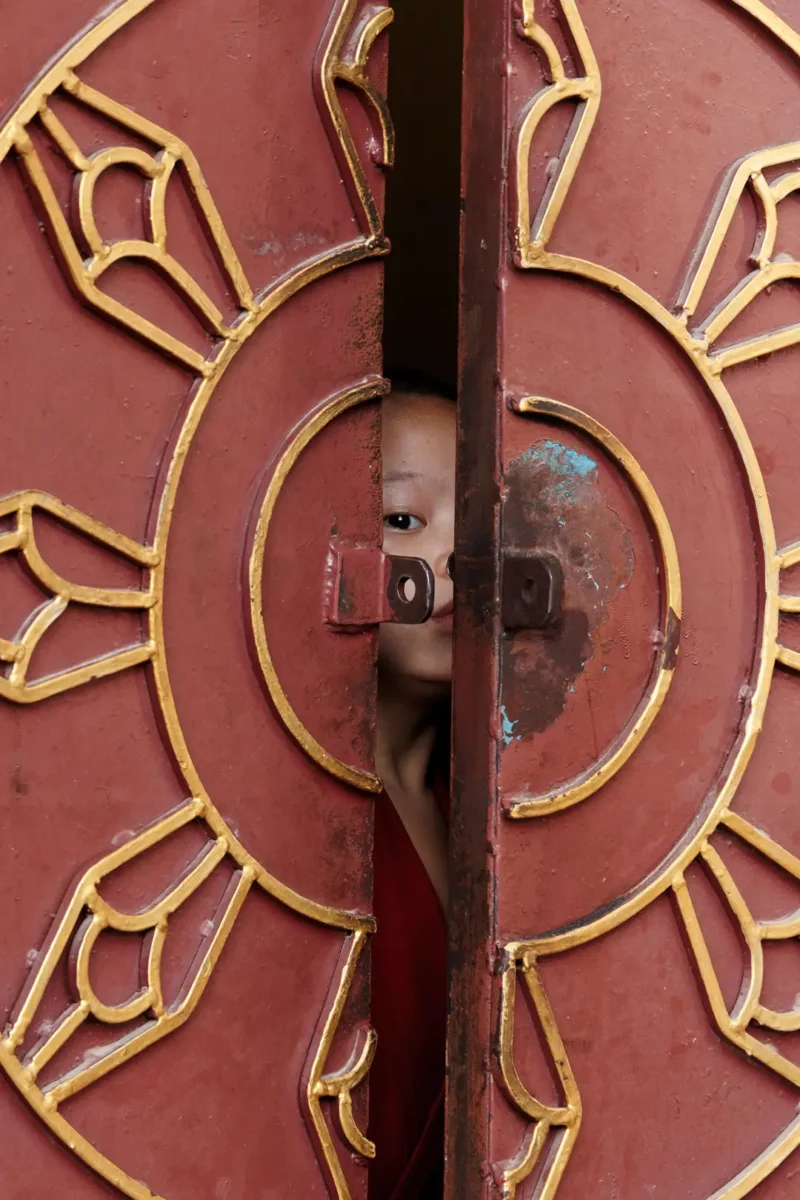 Young Monk looking through the door of a temple, Kathmandu Nepal