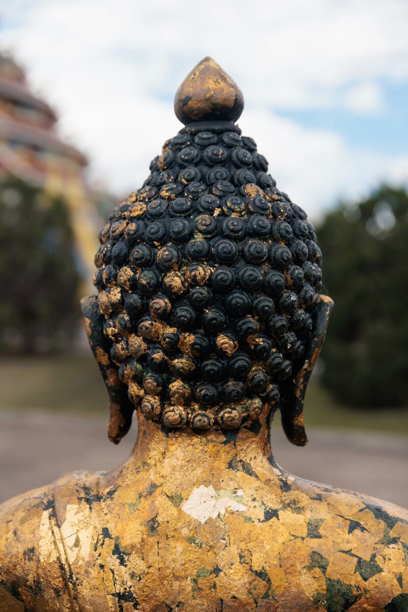 Buddha with gold on his back as part of the buddhist merit - Chiang Rai Thailand