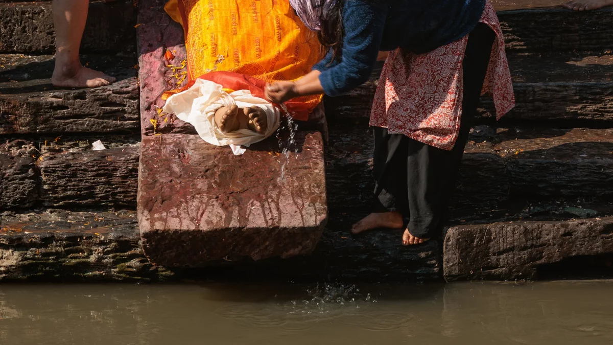 Believer washing the feet of a dead person in the Bagmati river, Pashupatinath temple Nepal