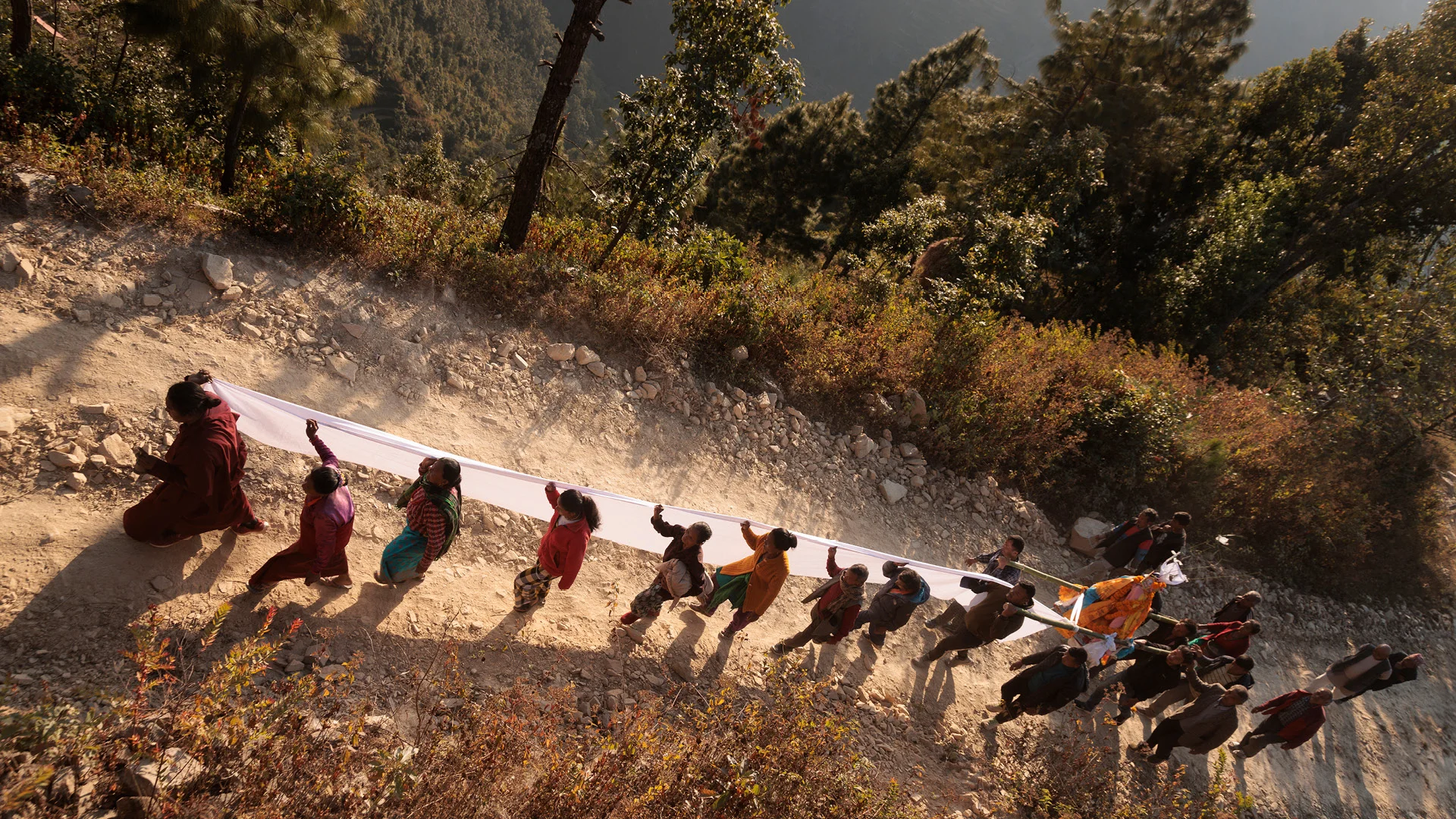 Women holding a white banner on the way to a sacred cremation ground in remote village of nepal