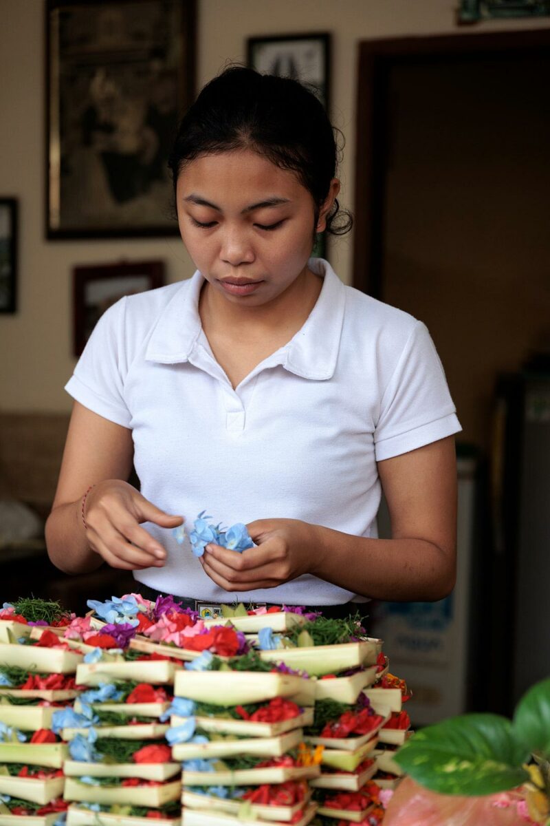 young women preparing basket of flower offering in ubud, Bali Indonesia