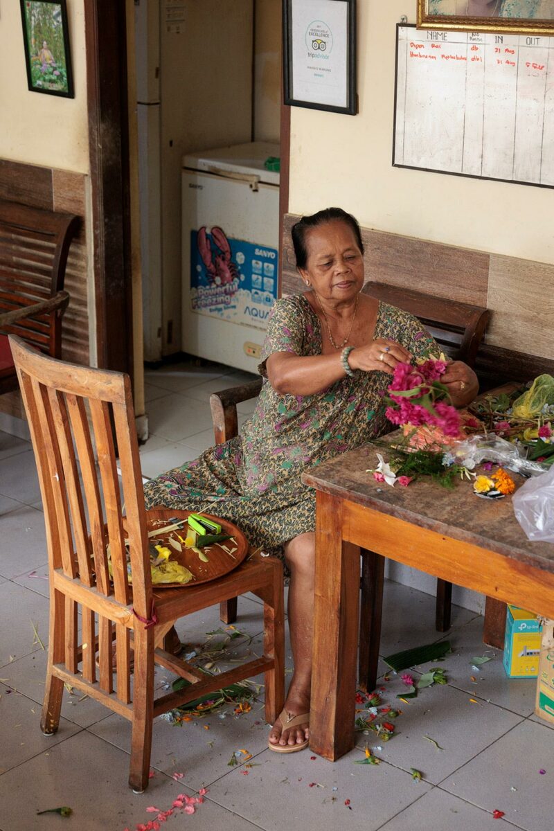 Ni Nyoman Badri preparing hindu flower offering in Bali Indonesia